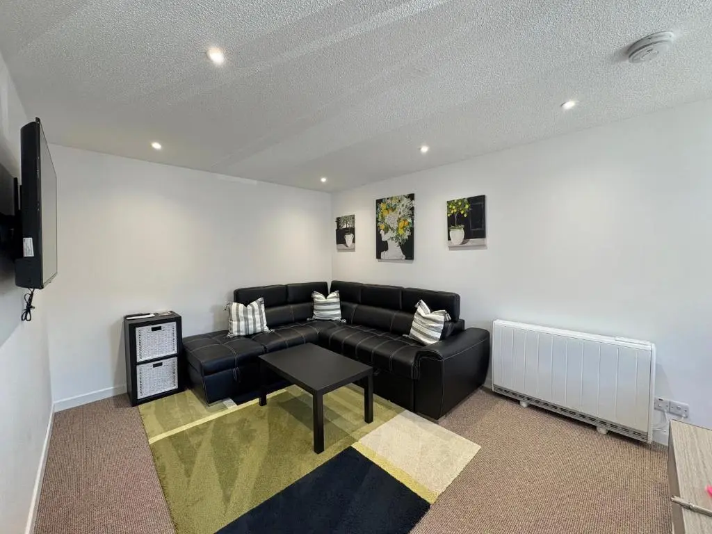 a living room with a black couch and a table at Elegant Apartment In City Centre in Inverness