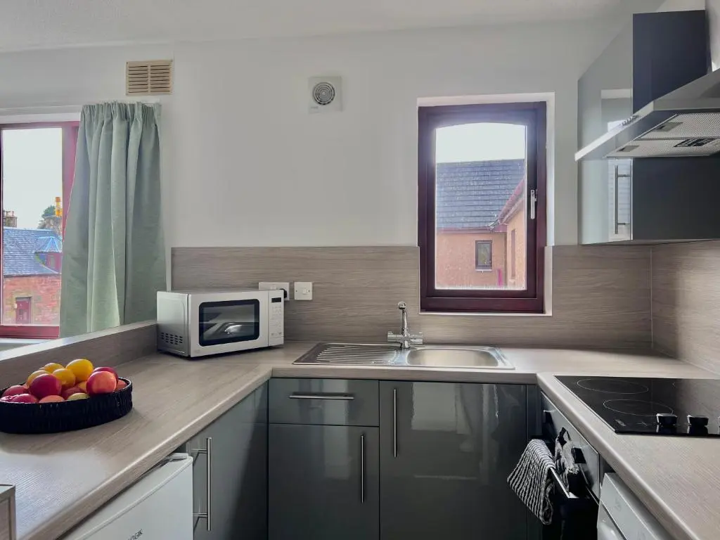 a kitchen with a sink and a microwave and a bowl of fruit at Elegant Apartment In City Centre in Inverness