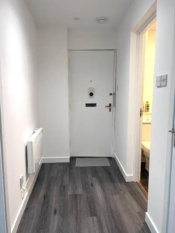 an empty hallway with a white door and wooden floors at Elegant Apartment In City Centre in Inverness