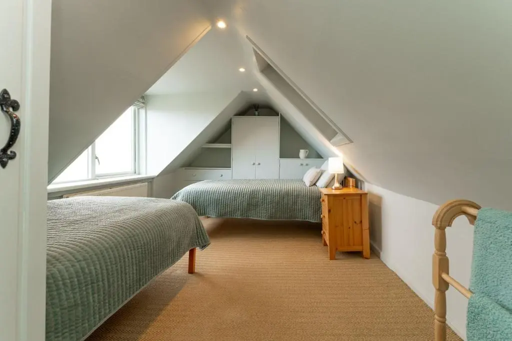 a attic bedroom with two beds and a window at Fishermans Cottage in Lossiemouth