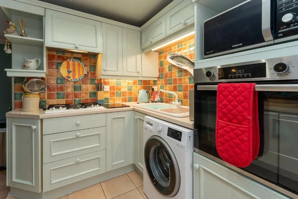 a kitchen with a washing machine and a sink at Fishermans Cottage in Lossiemouth