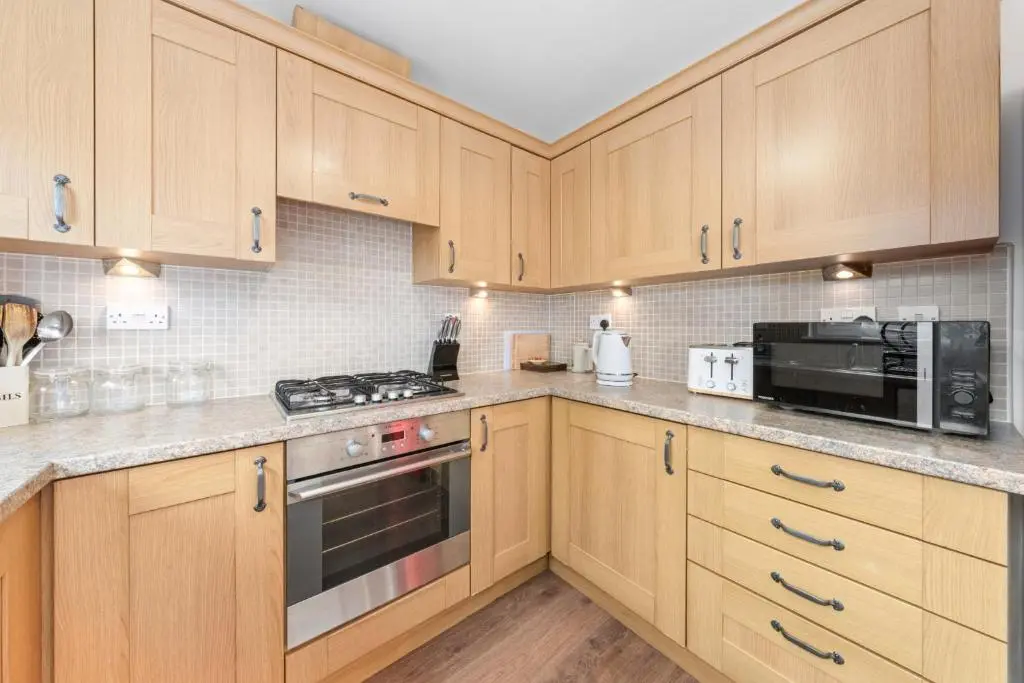 a kitchen with wooden cabinets and a stove top oven at Pinewood 3 Bedroom House in Inverness with Views in Inverness