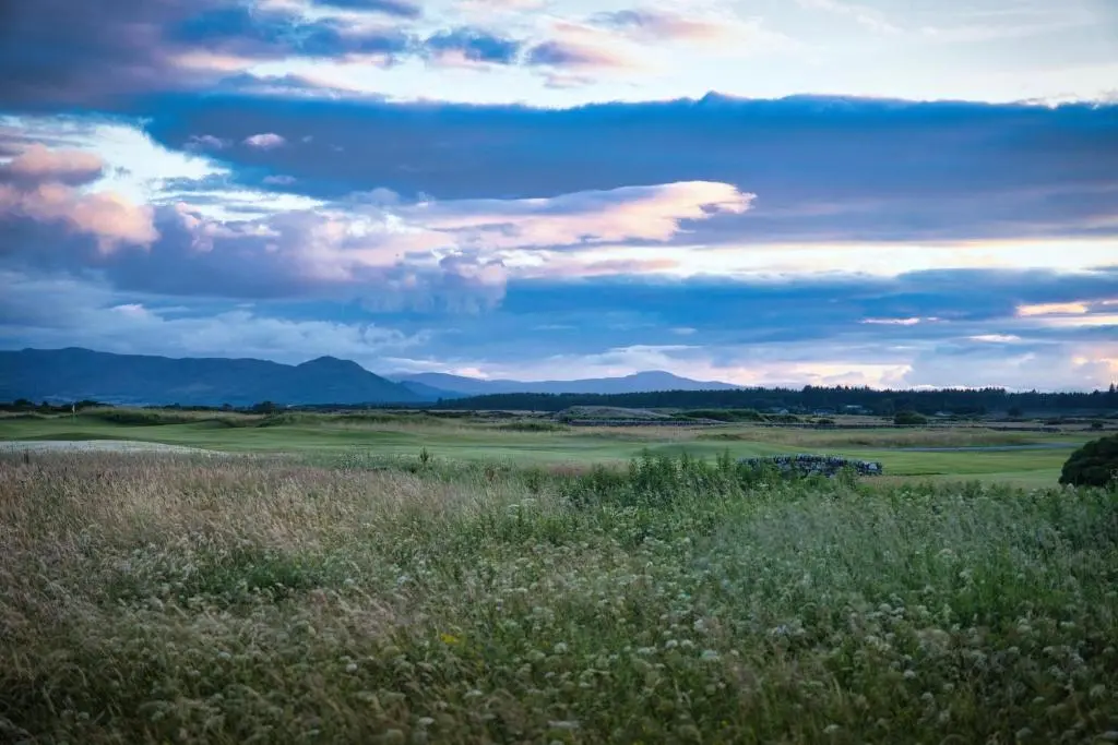 a field of grass with mountains in the background at Struie Bothy near Dornoch Beach in Dornoch