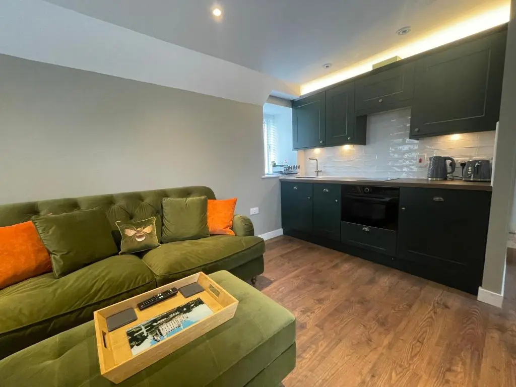 a living room with a green couch and a kitchen at Struie Bothy near Dornoch Beach in Dornoch