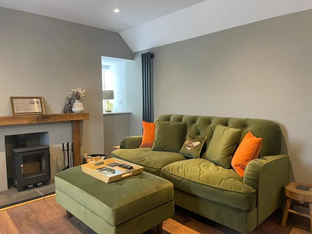 a living room with a green couch and a fireplace at Struie Bothy near Dornoch Beach in Dornoch