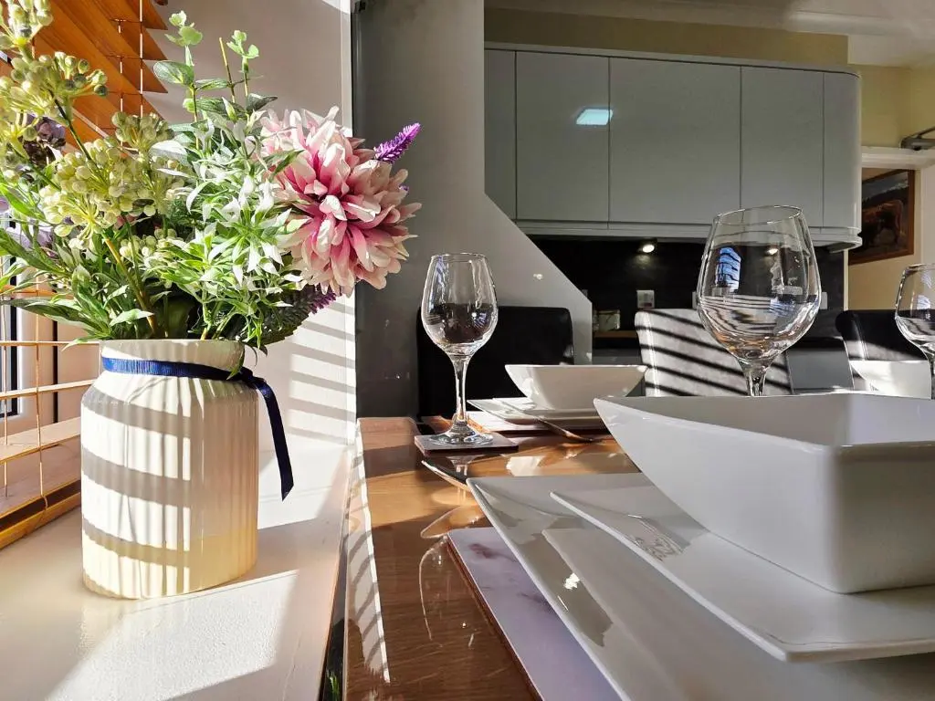 a vase of flowers on a table with wine glasses at Inverness City 4 Bedroom house free parking in Inverness