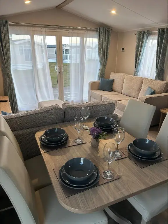 a living room with a table with plates and wine glasses at Silversands holiday park new caravan in Lossiemouth