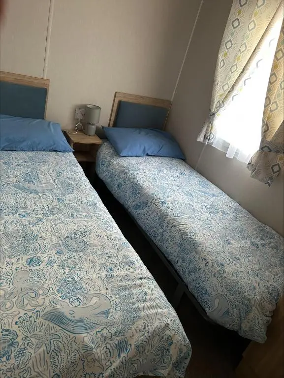 two beds in a small room with a window at Silversands holiday park new caravan in Lossiemouth