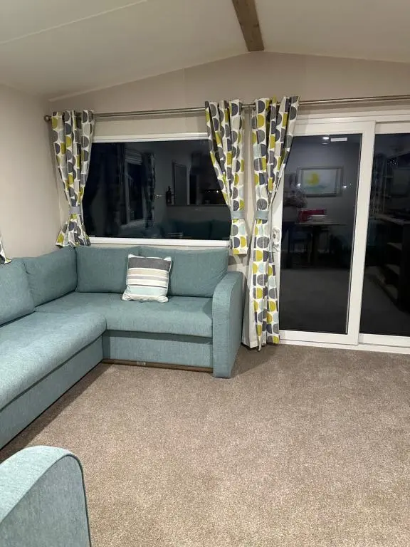 a living room with a blue couch and curtains at Silver Dunes in Lossiemouth