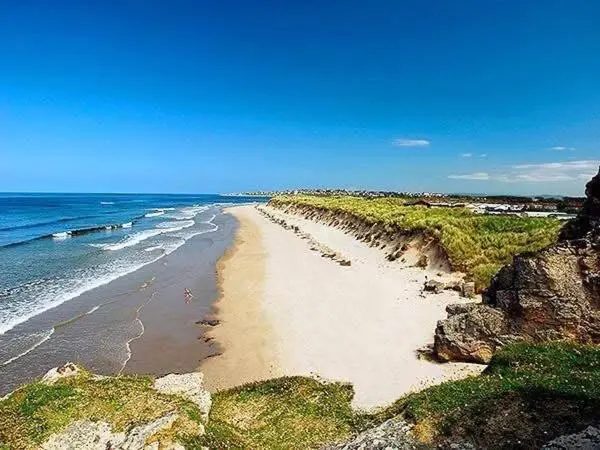 a sandy beach with the ocean and a blue sky at Silver Dunes in Lossiemouth