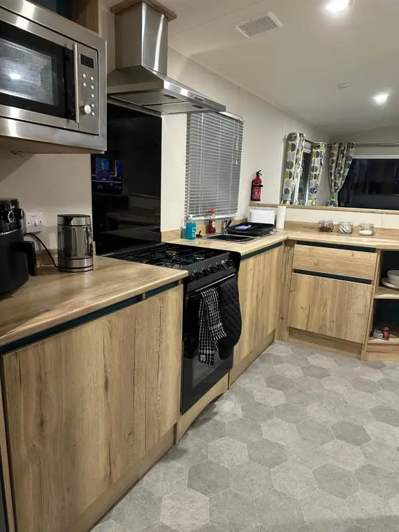 a kitchen with wooden cabinets and a stove top oven at Silver Dunes in Lossiemouth