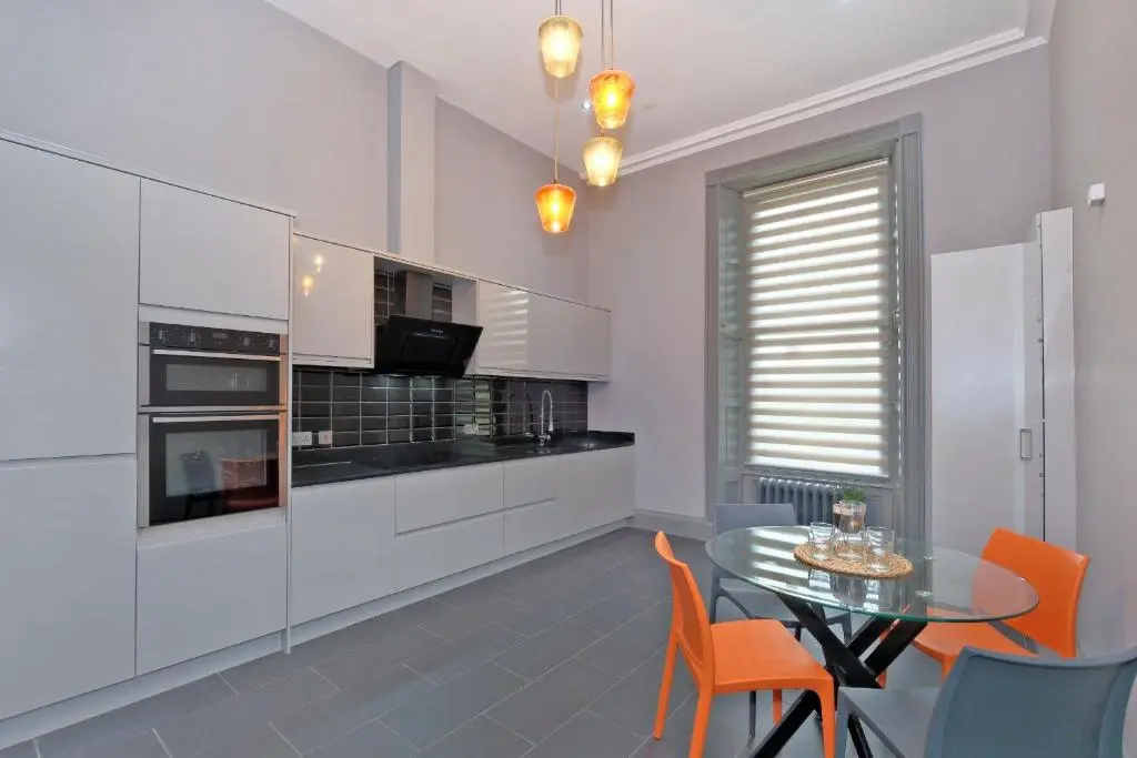 a kitchen with a glass table and orange chairs at Kirkton House in Kirkton of Skene