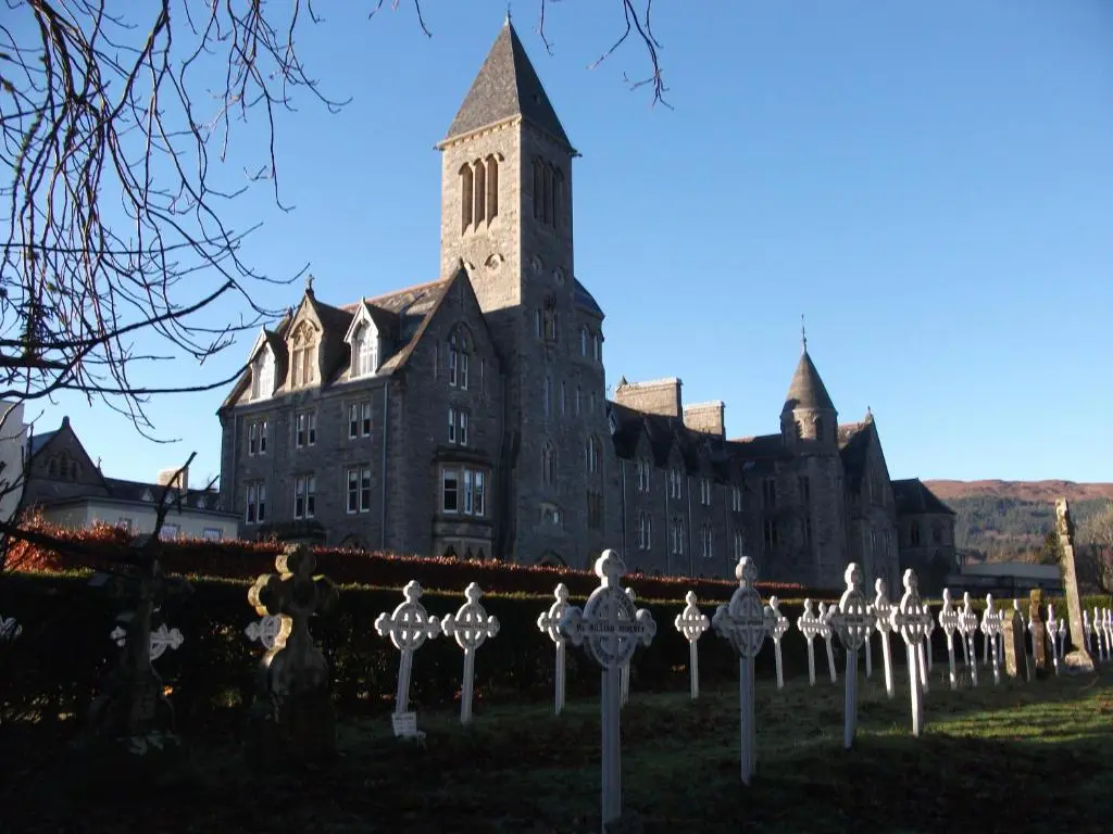 an old building with a clock tower in front of it at Moat House - Highland Club in Fort Augustus