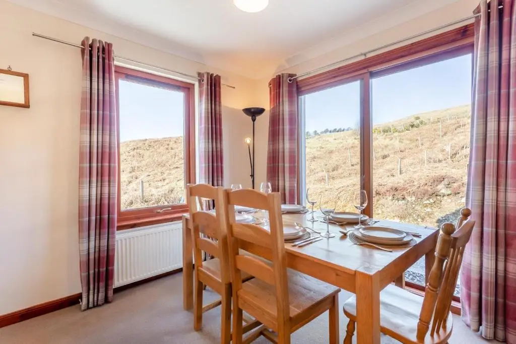 a dining room with a table and chairs and large windows at 3 Bed in Strathkanaird oc-r30948 in Ullapool