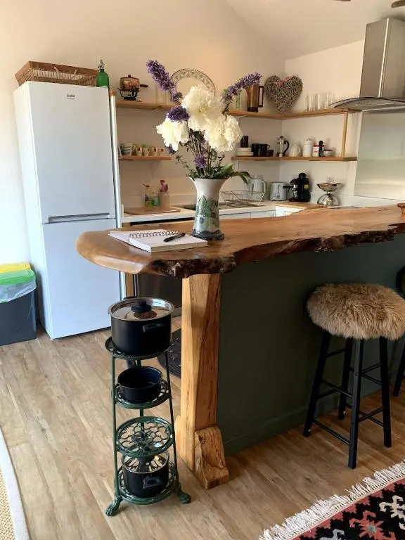 a kitchen with a wooden island with a vase of flowers at The Space at the Creamery - Royal Deeside in Torphins