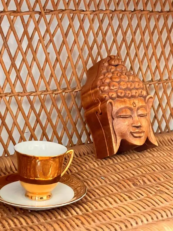 a cup on a plate next to a wooden head statue at The Space at the Creamery - Royal Deeside in Torphins