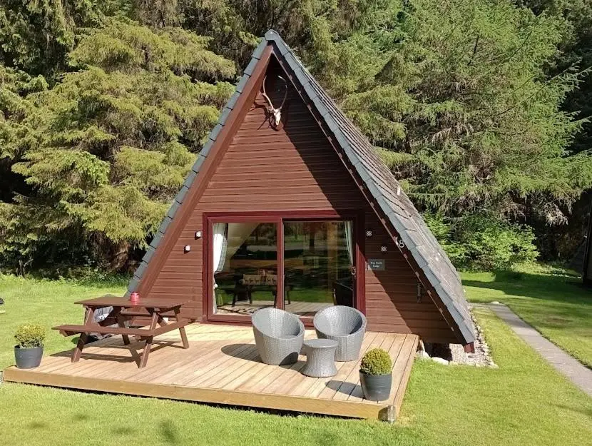 a small house with a picnic table and a bench at True North Lodge - A cosy wee highland Getaway in Spean Bridge