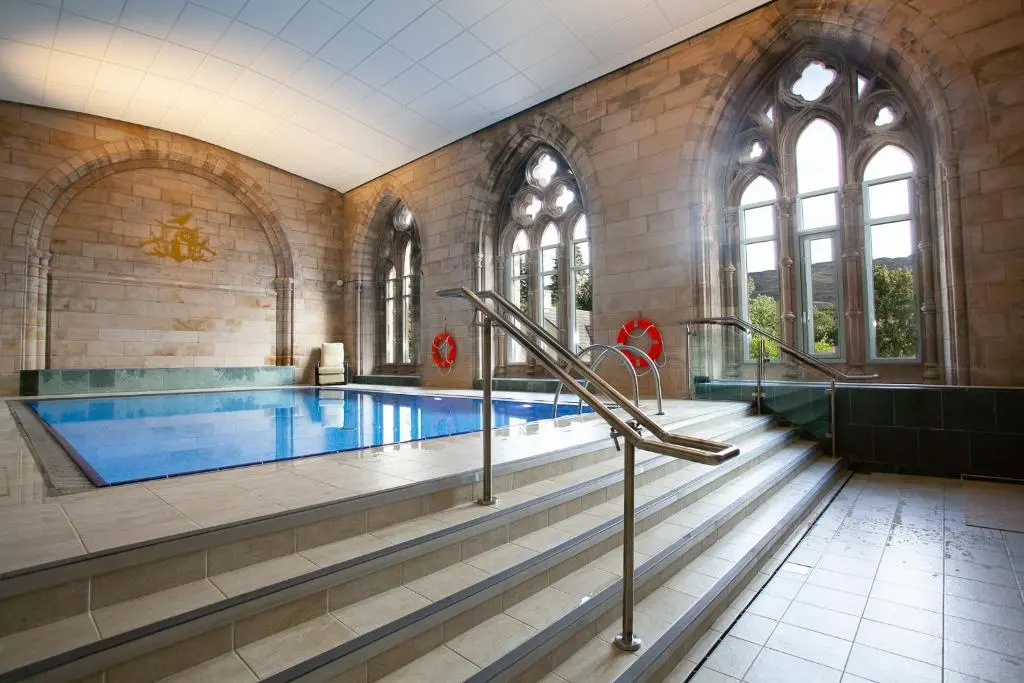 a large swimming pool in a building with a swimming pool at Highland Club Scotland Apartments in Fort Augustus