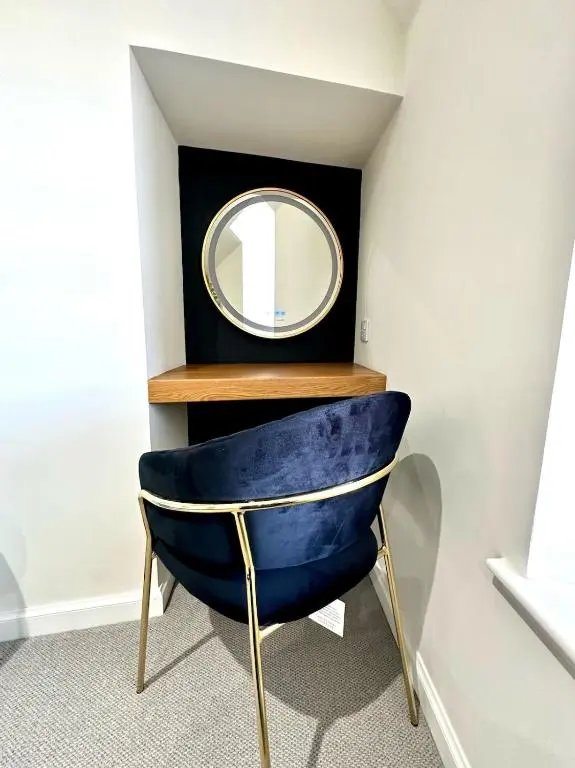 a blue chair with a mirror on a wall at Cozy Cottage Retreat in Portsoy