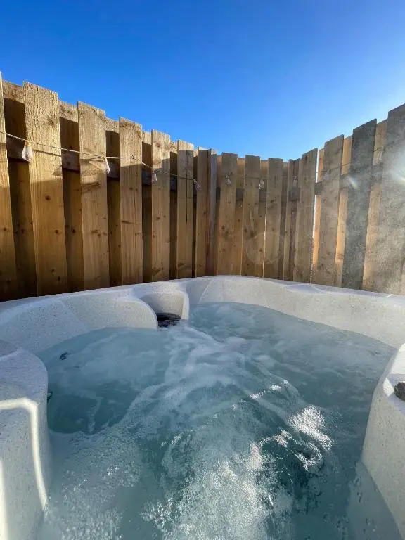 a hot tub in front of a wooden fence at Kaoglen - Alpine Pod - Hot Tub - Cairngorms - Pitlochry in Kirkmichael