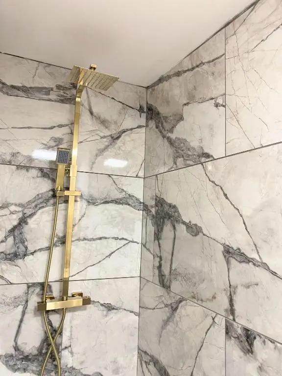 a shower in a bathroom with a marble wall at Kaoglen - Alpine Pod - Hot Tub - Cairngorms - Pitlochry in Kirkmichael
