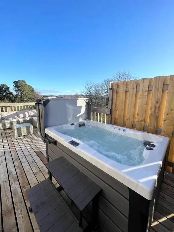 a hot tub on a deck with a fence at Kaoglen - Bali Pod - Hot Tub -Cairngorms - Pitlochry in Kirkmichael