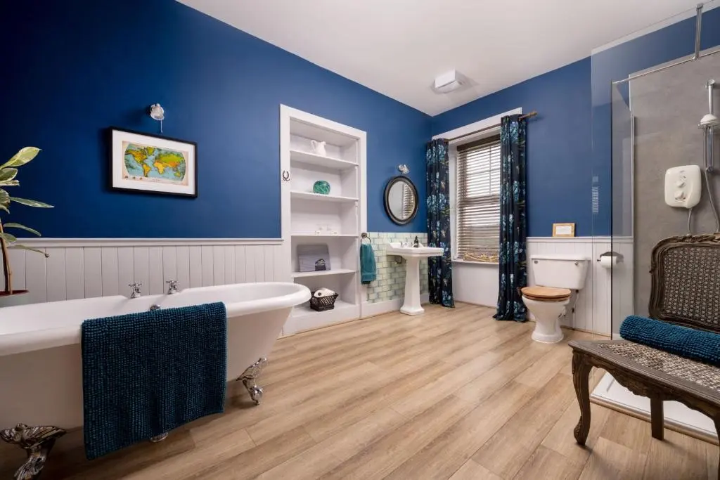 a blue bathroom with a tub and a toilet at Old Duffus Farmhouse in Duffus
