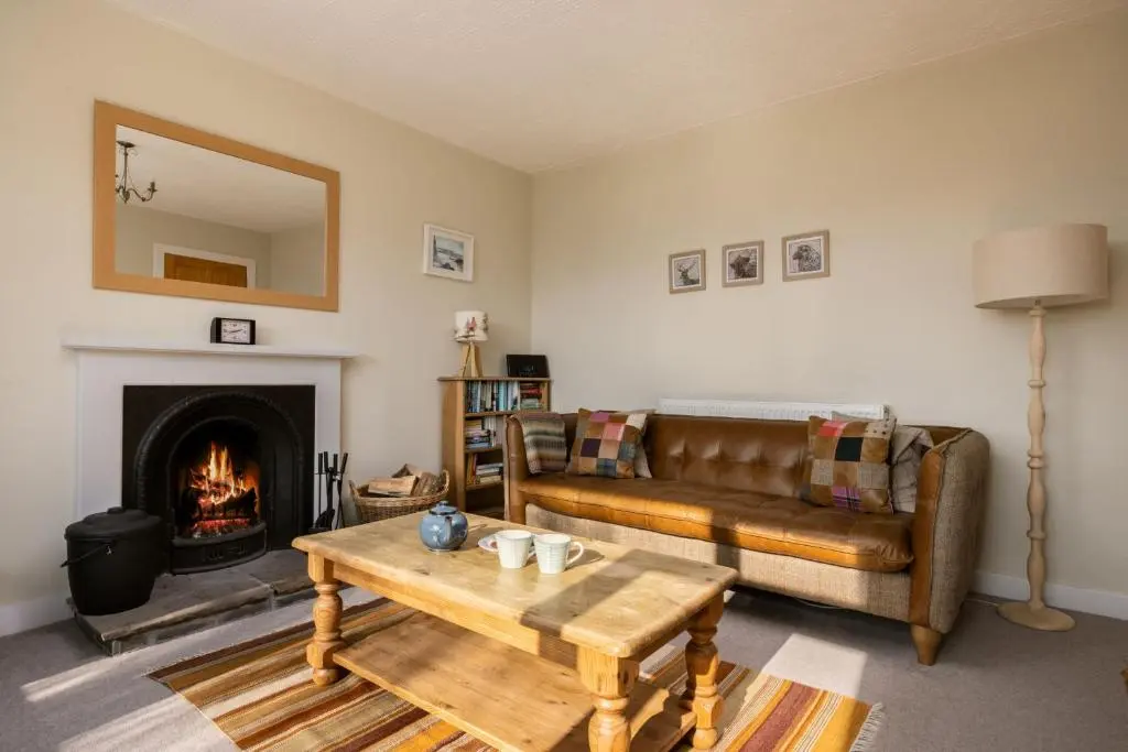 a living room with a couch and a fireplace at Kirktoun Cottage in Duffus