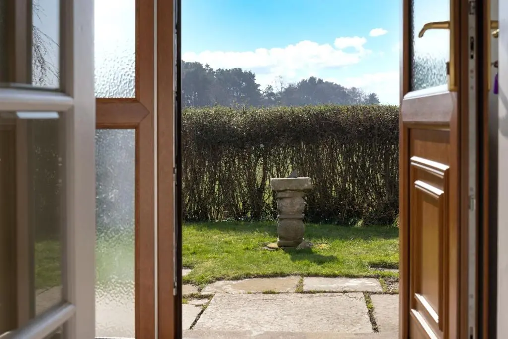 an open door to a yard with a stone pillar at Kirktoun Cottage in Duffus