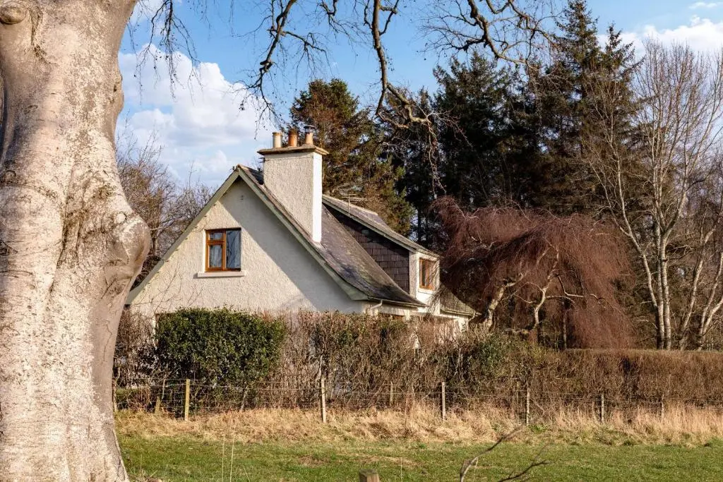 an old house in a field next to a tree at Kirktoun Cottage in Duffus