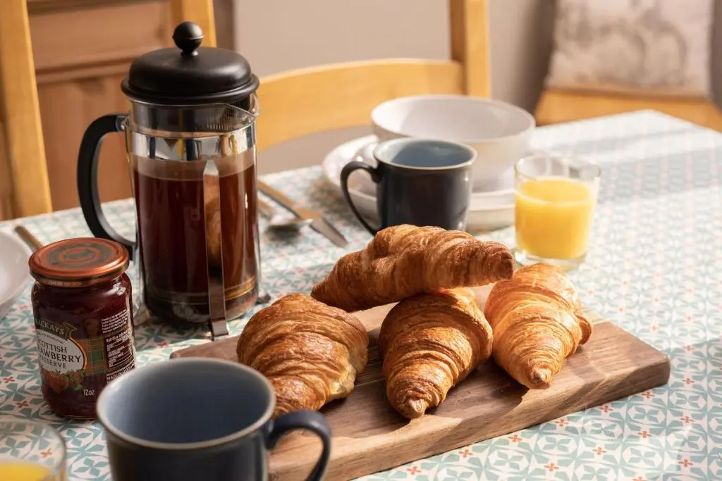 a wooden cutting board with croissants on a table at Kirktoun Cottage in Duffus