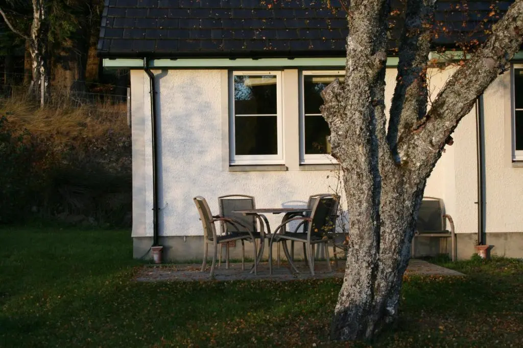 a table and chairs in front of a house at BCC Loch Ness Cottages in Drumnadrochit