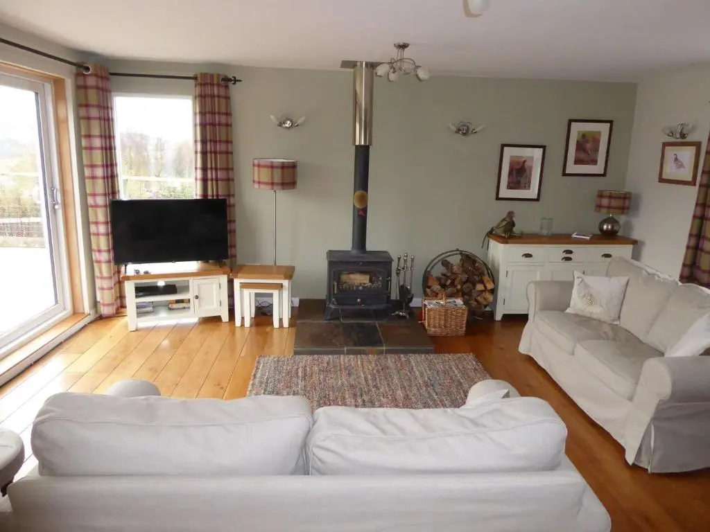 a living room with a white couch and a fireplace at Groose Hoose in Glenshee