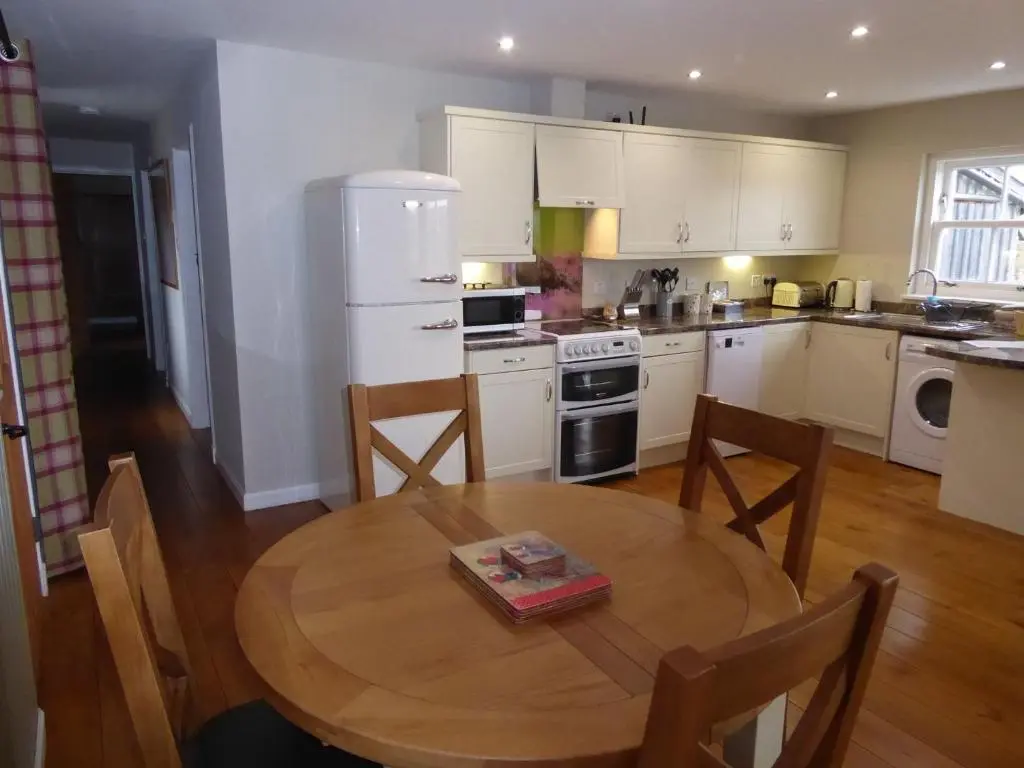 a kitchen with a wooden table and a wooden floor at Groose Hoose in Glenshee