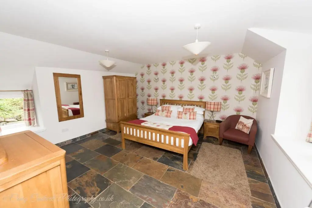 a bedroom with a bed and a chair at Coo Shed in Glenshee