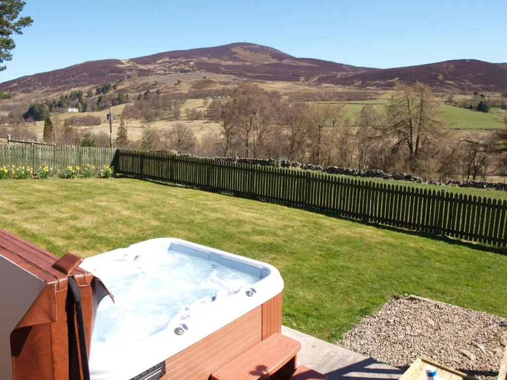 a hot tub in a yard with a hill at Coo Shed in Glenshee