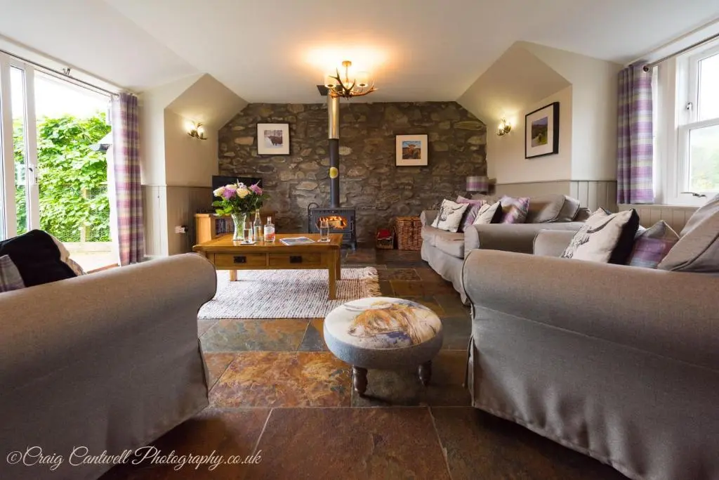 a living room with couches and a stone wall at Coo Shed in Glenshee