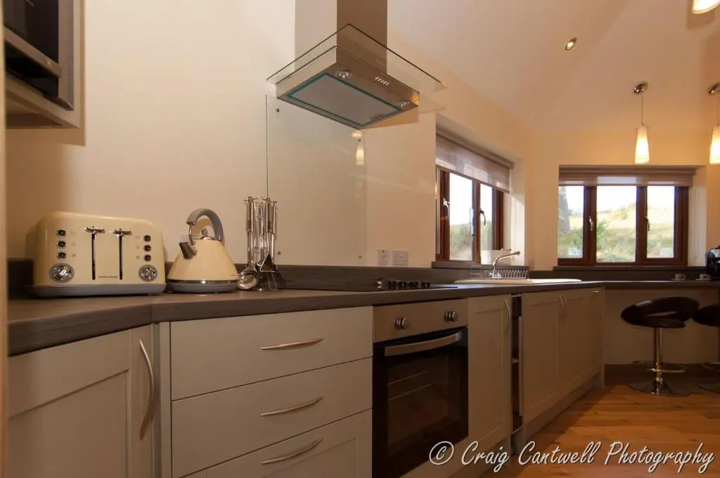 a kitchen with white cabinets and a counter top at Scots Pine Treehouse in Glenshee