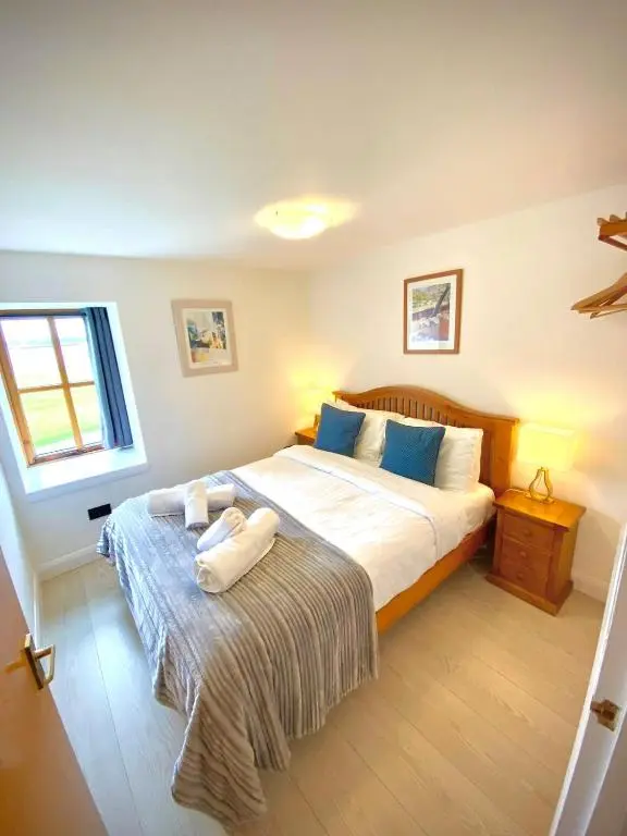 a bedroom with a large bed with blue pillows at Dolphin Bay Suites in Ardersier