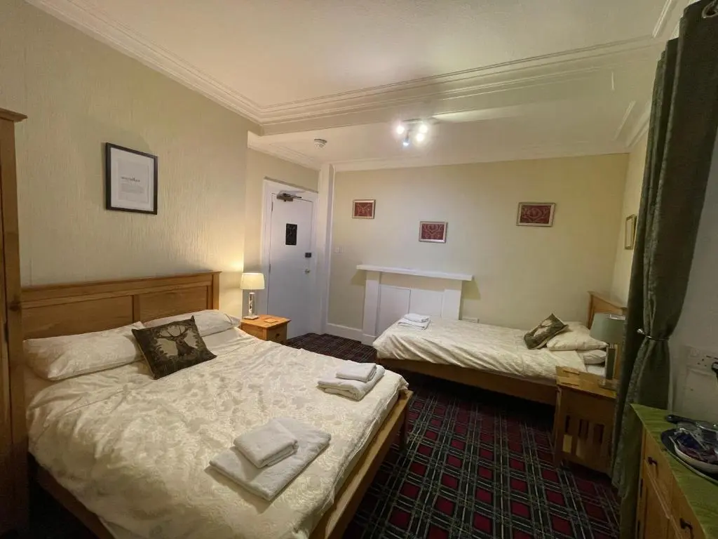 a bedroom with two beds and a table in it at Stag and Barrel in Elgin