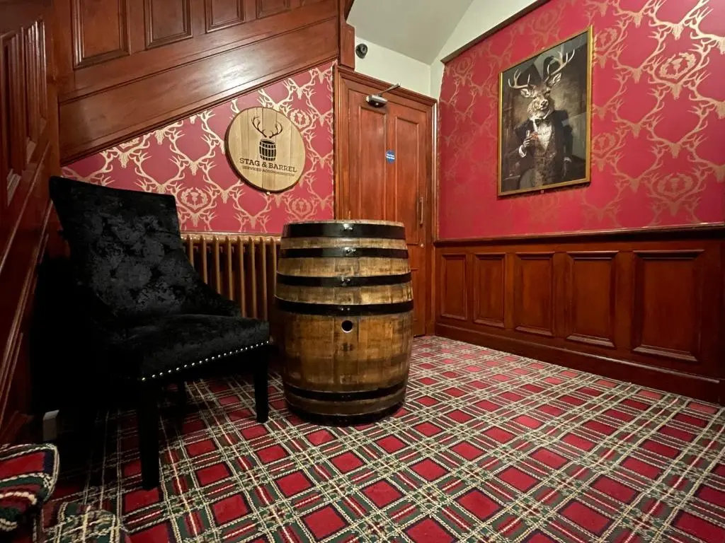 a room with a barrel and a chair and red walls at Stag and Barrel in Elgin