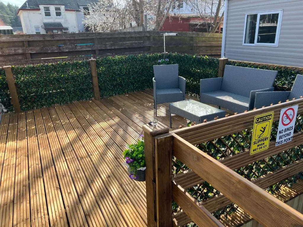 a wooden deck with two chairs and a table at The Highland Getaway 43 in Boat of Garten