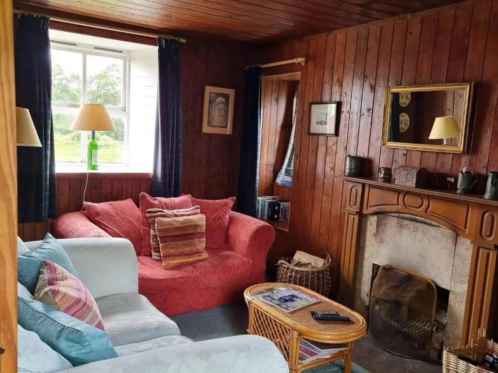 a living room with a red couch and a fireplace at Strathnoon in Inverness