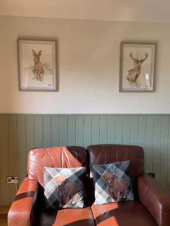 a brown leather couch with two cats sitting on it at The Wee Knoll in Invergarry