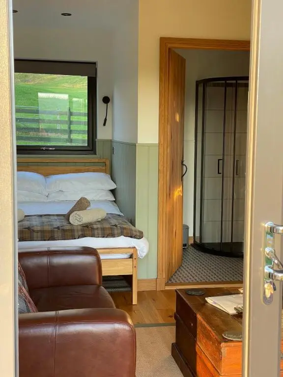 a bedroom with a bed and a couch and a window at The Wee Knoll in Invergarry