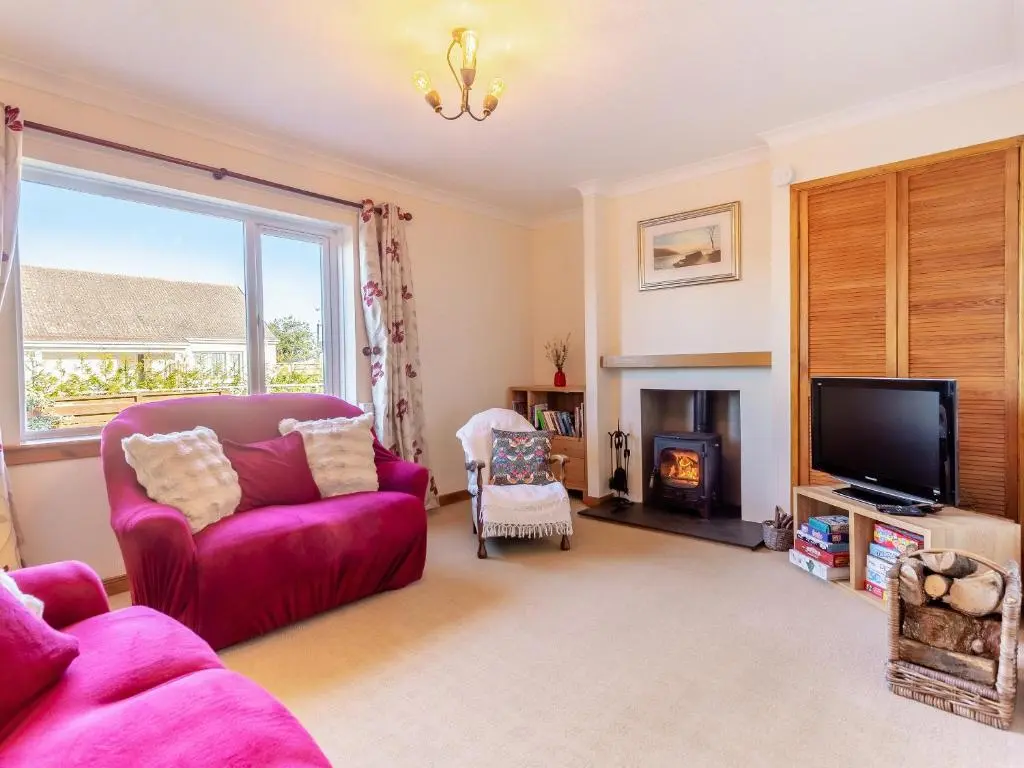 a living room with a red couch and a fire place at The Cherry Tree in Cawdor