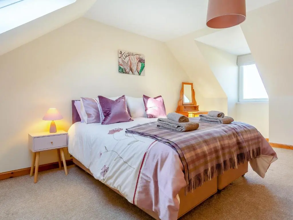 a bedroom with a large bed with purple pillows at The Cherry Tree in Cawdor