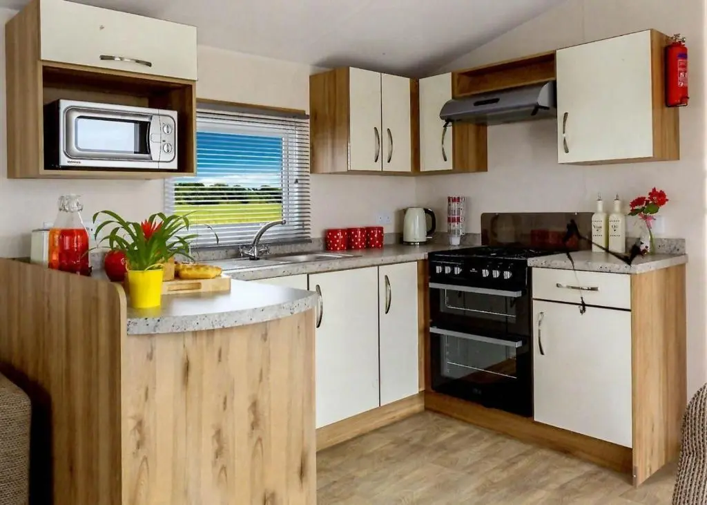 a kitchen with white cabinets and a black stove top oven at Findhorn Bay - Mobile Holiday Homes in Findhorn
