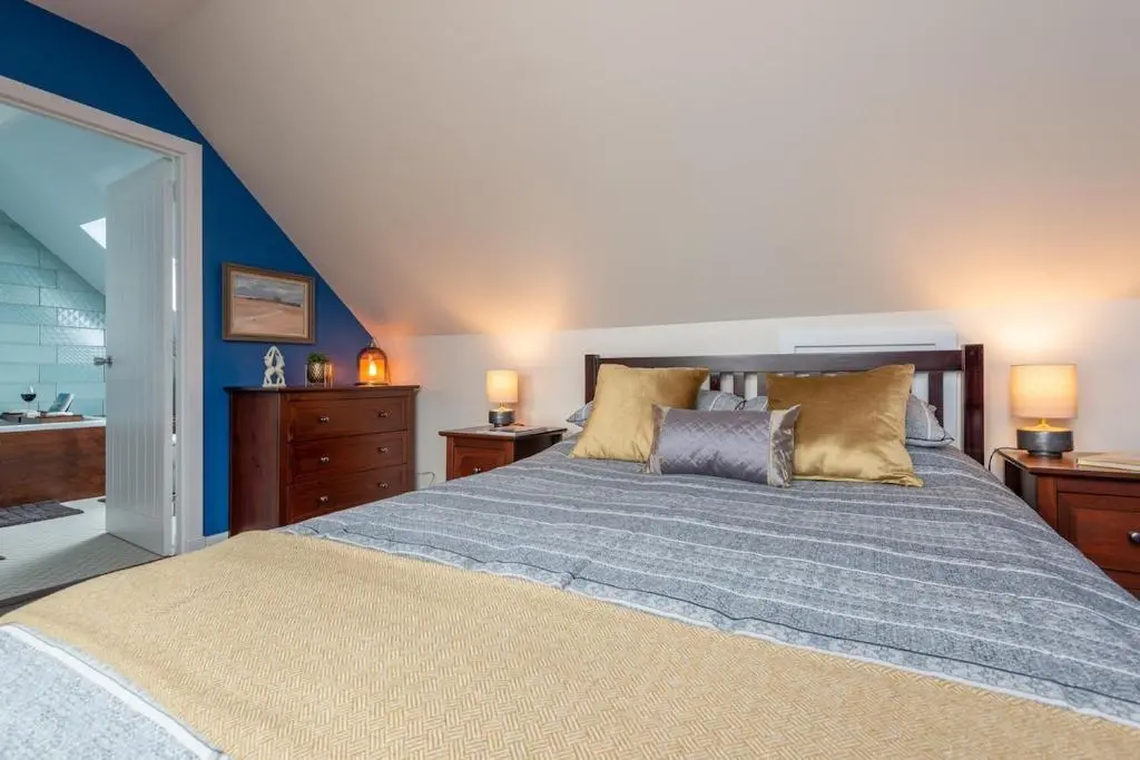 a bedroom with a large bed with two lamps and a sink at An I\u00f9bhrach in Inverness