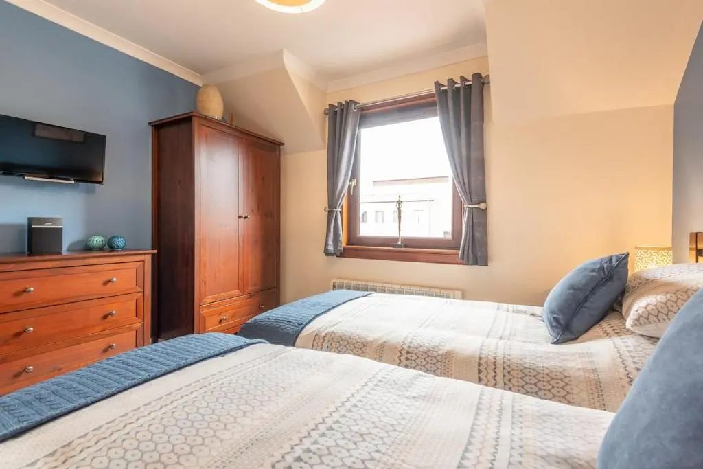 a bedroom with two beds and a window at An I\u00f9bhrach in Inverness